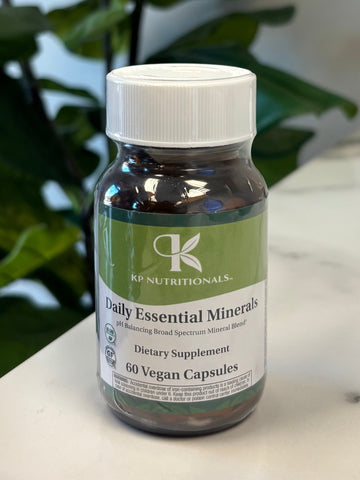 Bottle of Daily Essential Minerals with a plant in the foreground on a marble surface