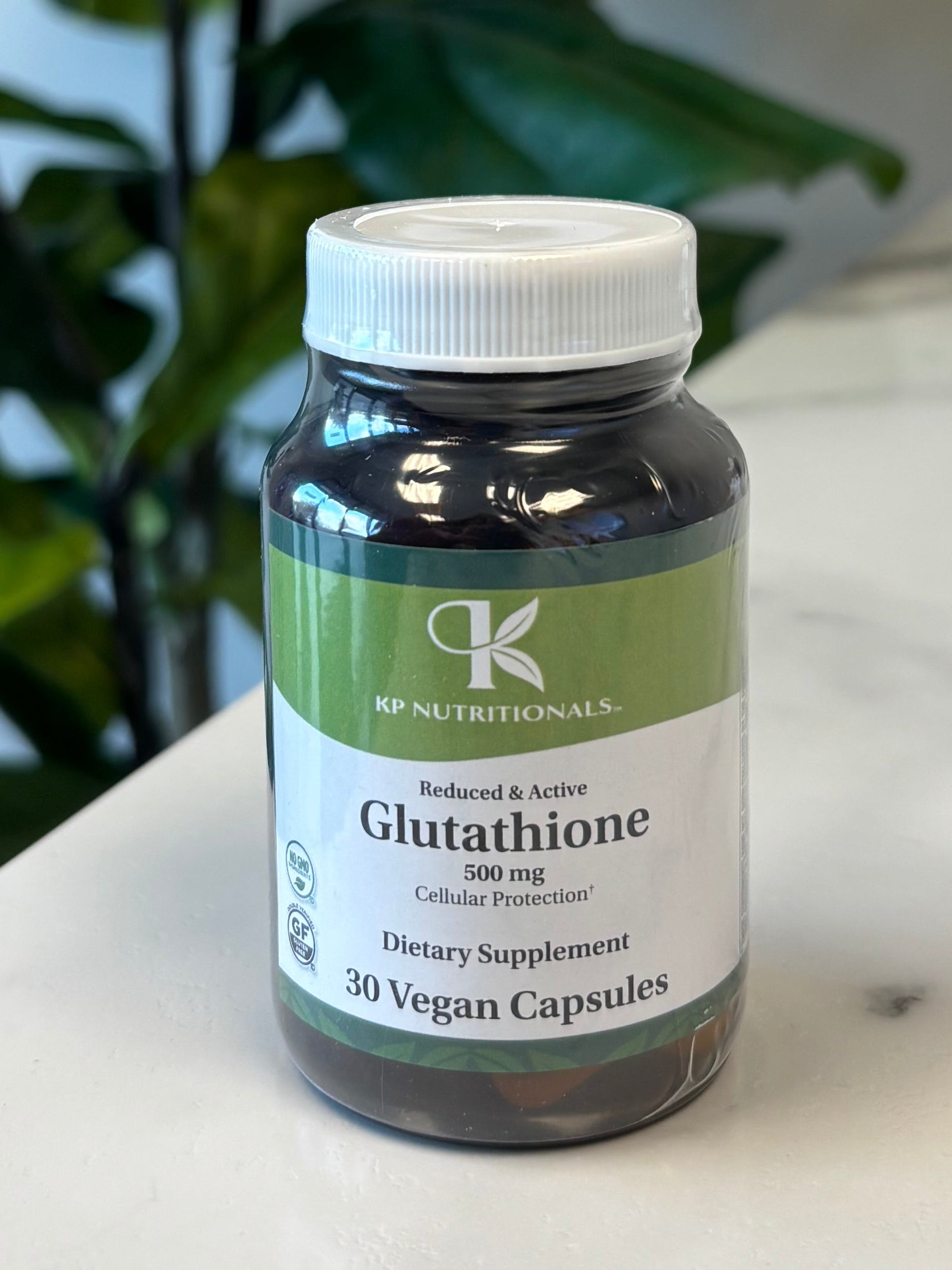 Bottle of Glutathione on a marble surface with a plant in the foreground