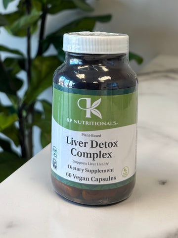 Supplement bottle labeled 'Liver Detox Complex' on a marble surface with a plant in the foreground