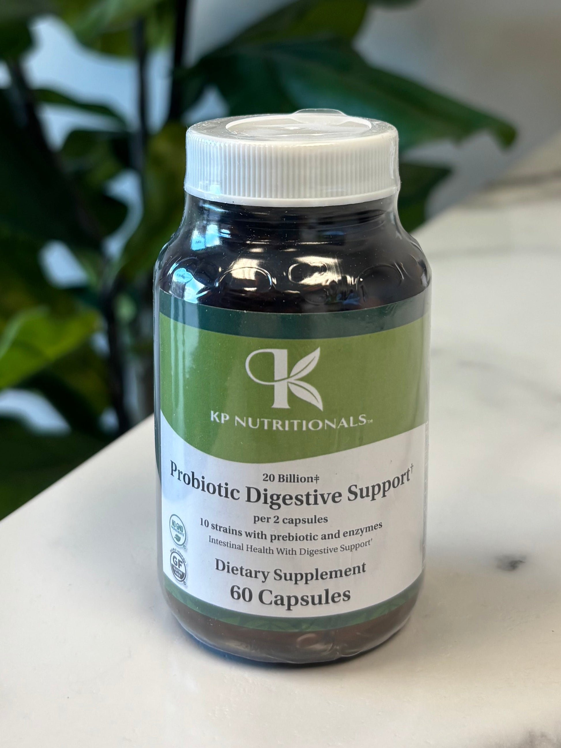 Supplement bottle Probiotic Digestive Support on a marble surface with a plant in the foreground