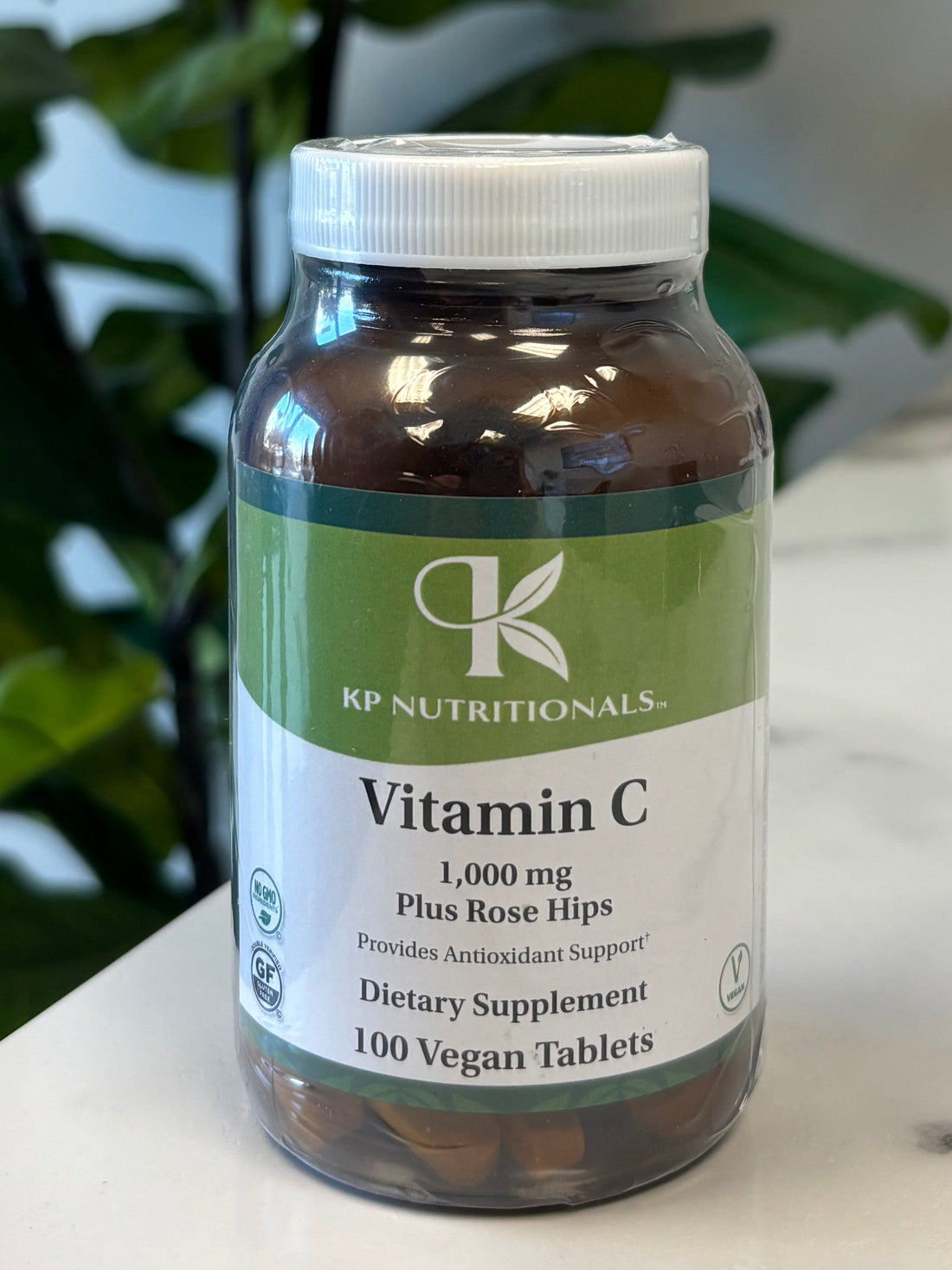 Vitamin C supplement on a marble surface with green leaves in the foreground