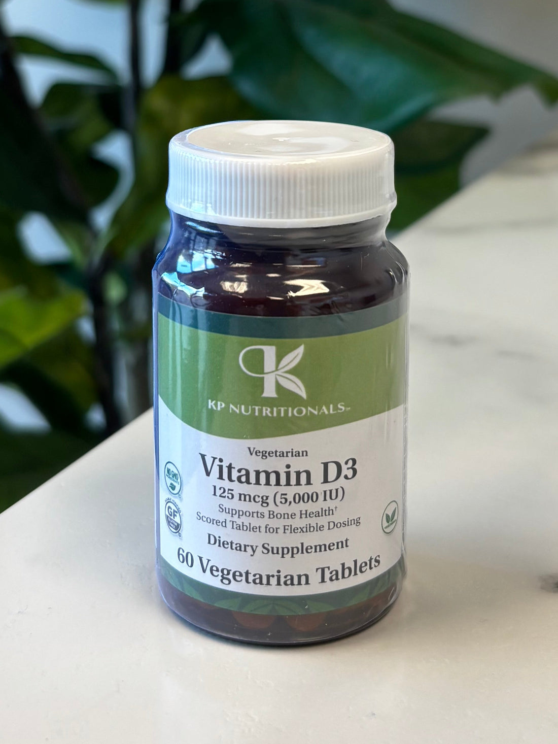 Vitamin D3 supplement bottle on a marble surface with a plant in the foreground