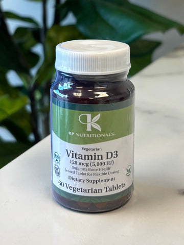 Vitamin D3 supplement bottle on a marble surface with a plant in the foreground